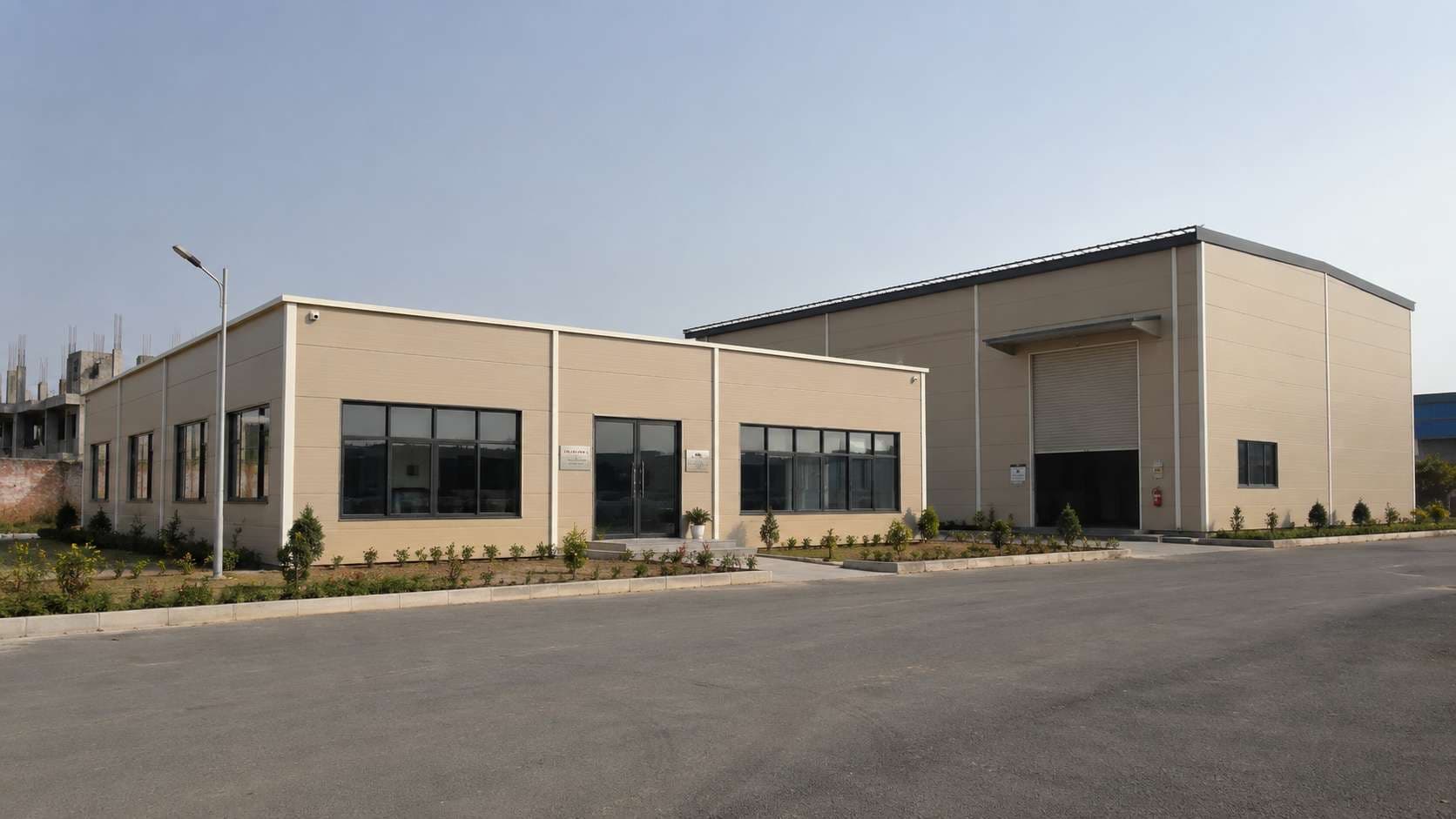 Two sandstone-beige prefabricated buildings of different types — an office and a light-industrial unit.