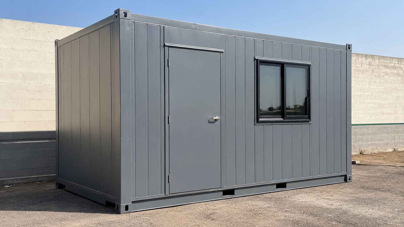 Steel grey container building on a compacted base showing the 20-foot front face.