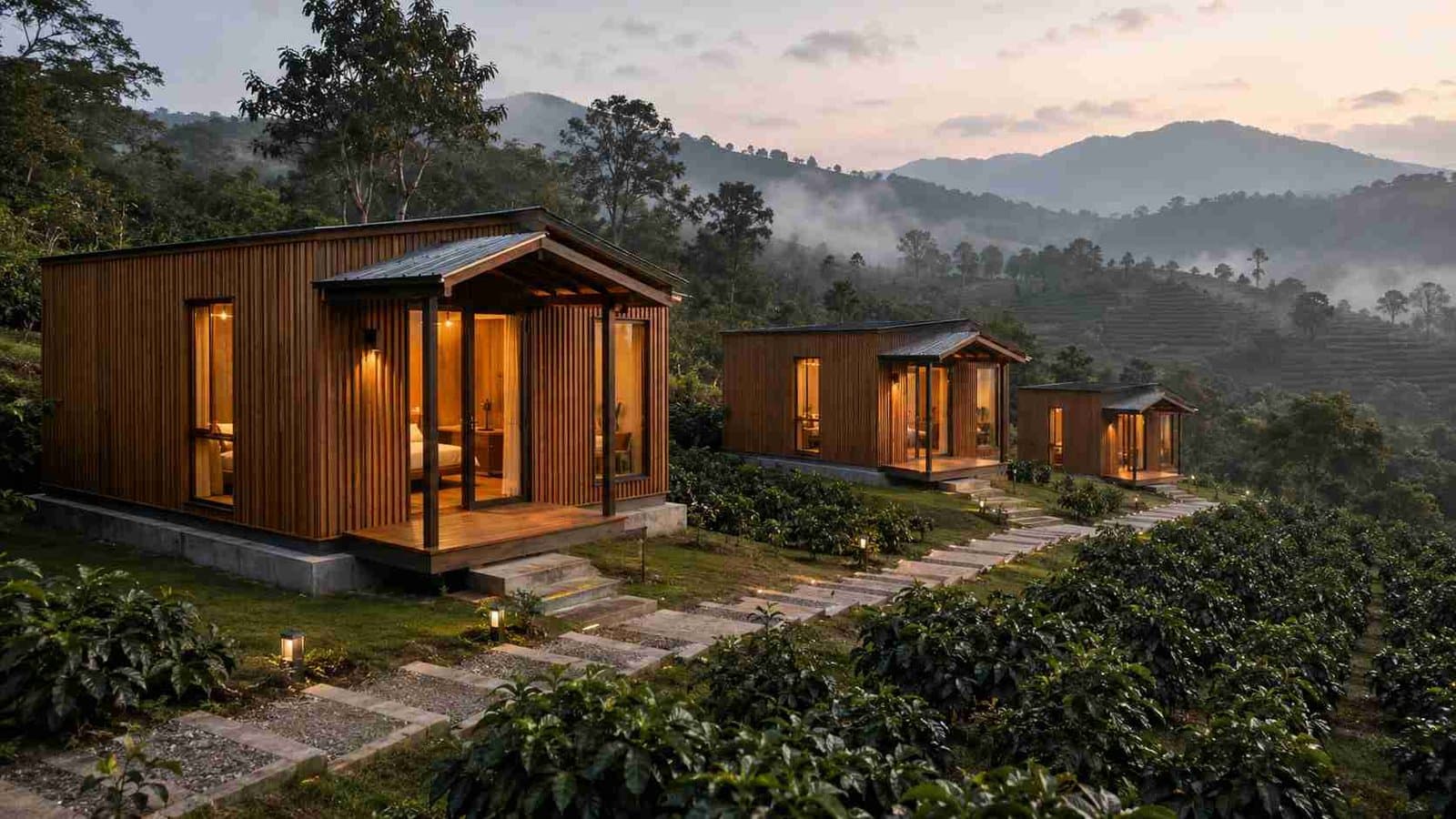 Three wood-batten container hotel cottages stepped down a Coorg coffee-estate slope with misty hills in the distance — boutique coffee-stay deployment