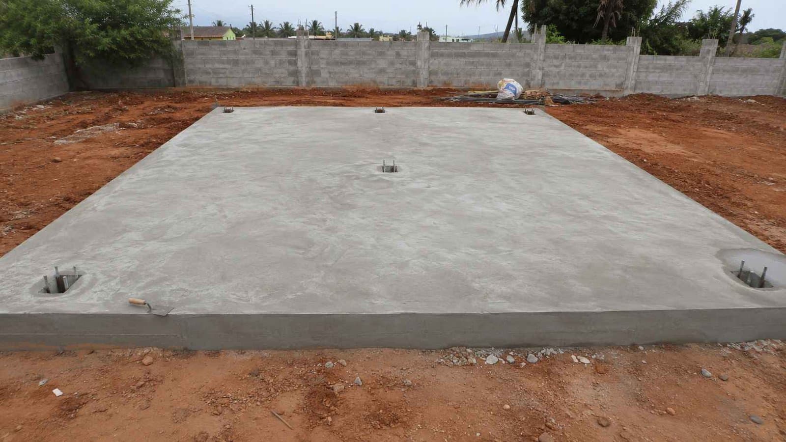 Freshly finished 42×36 ft RCC plinth foundation on a cleared rural plot, prepared for inexpensive container home placement.