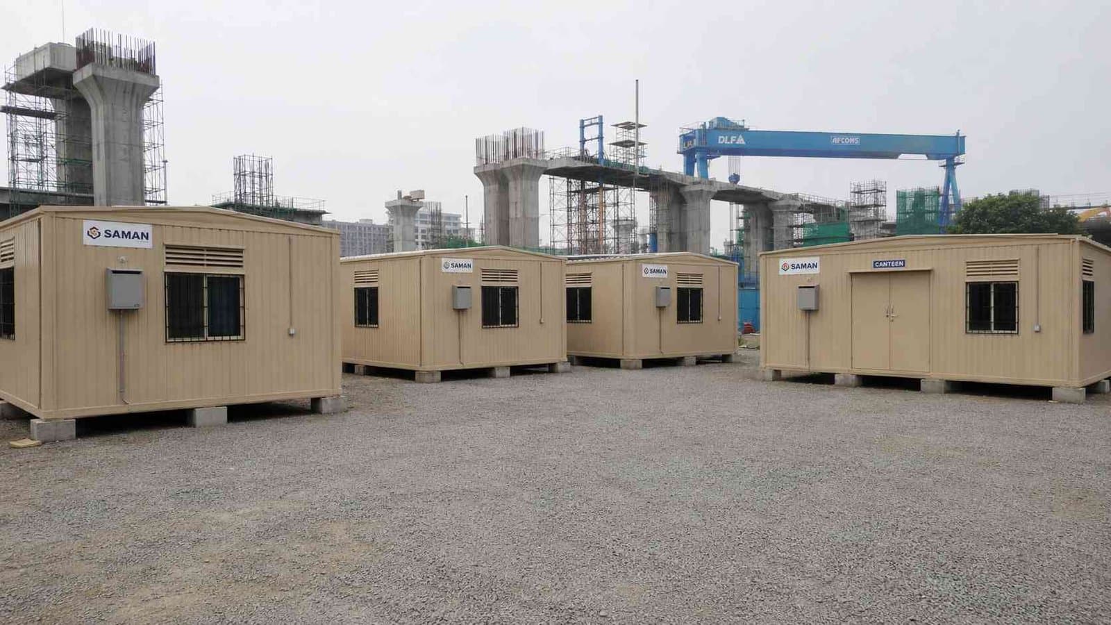 A sandstone beige labor camp with dormitory blocks and a canteen block deployed at a metro rail construction site.