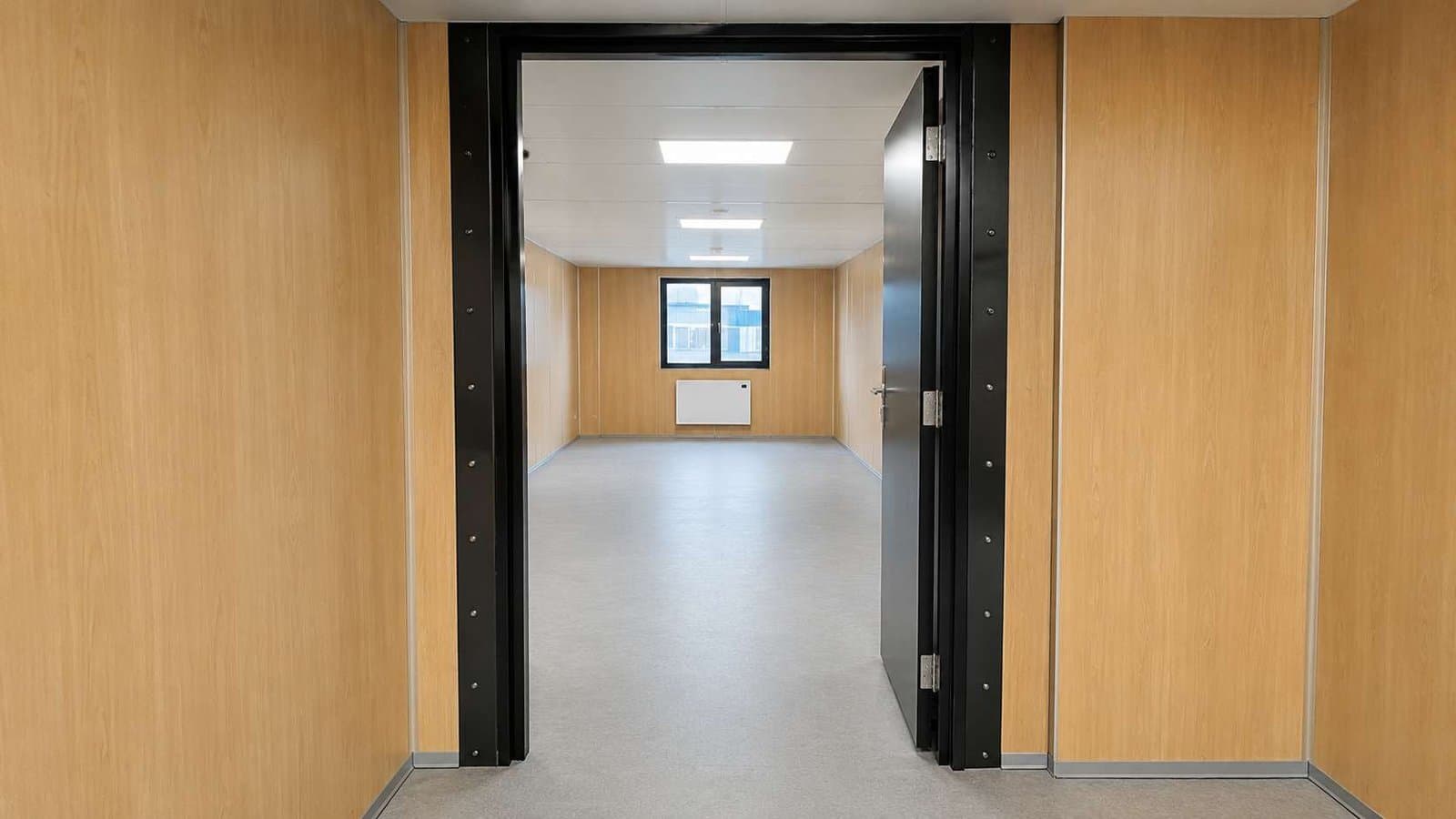 Interior doorway connecting two modular portable office modules showing level vinyl floor and bolted steel frame join