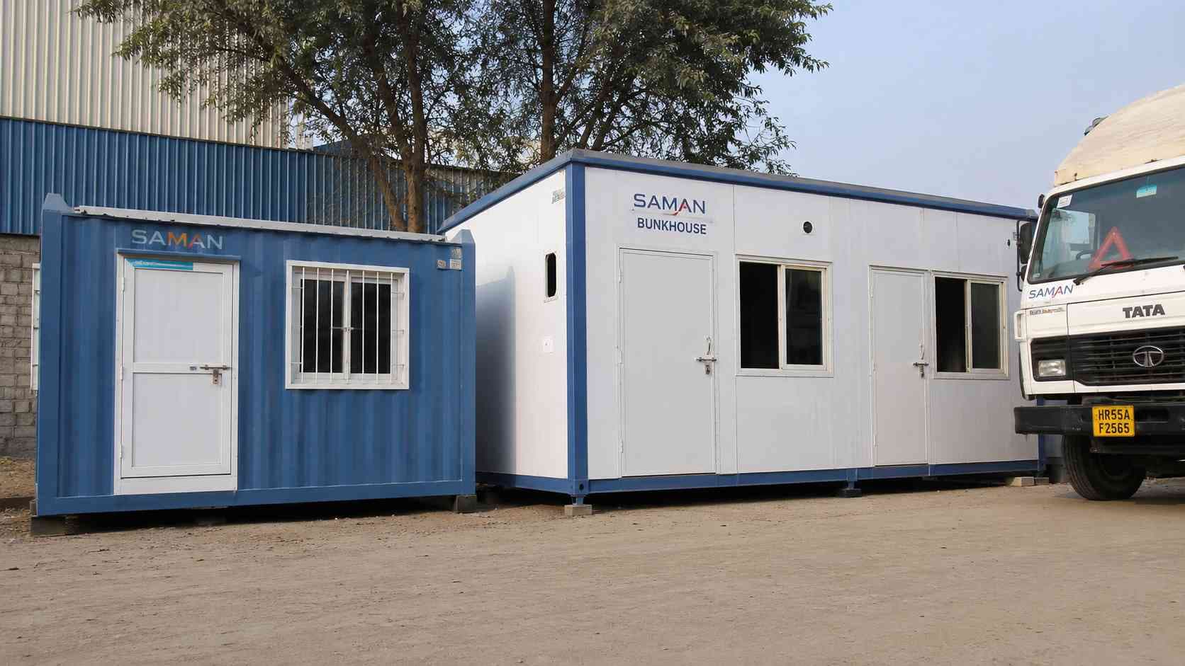 A steel blue porta cabin house beside a larger bunkhouse unit in SAMAN's prefab house range.