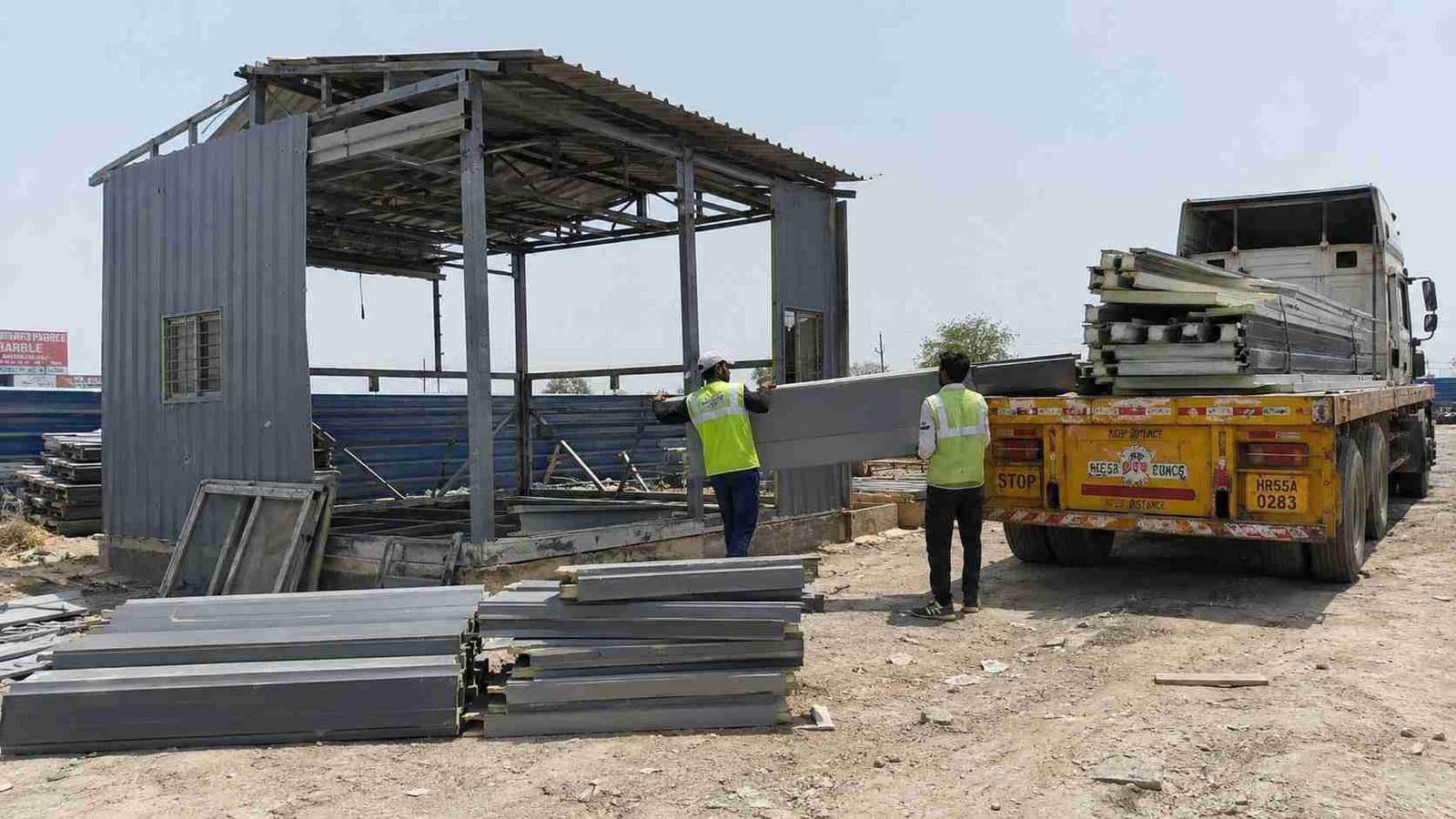 Steel-grey portable shed being dismantled and loaded onto a flatbed truck for relocation
