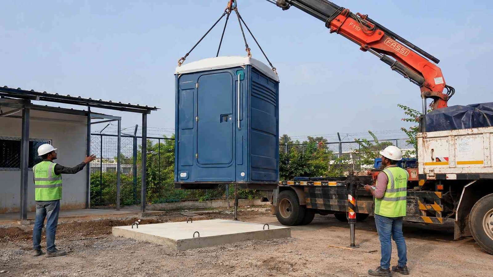 Portable toilet cabin being off-loaded by a truck-crane onto a level pad at a site