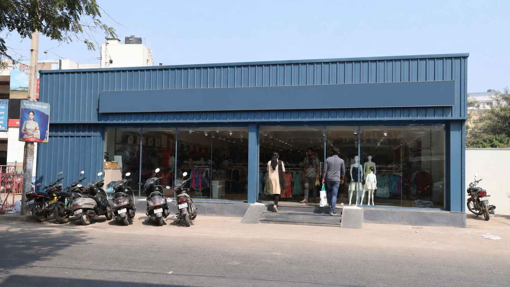 Steel-blue prefab commercial building used as a retail outlet with a glazed shopfront on an Indian street.