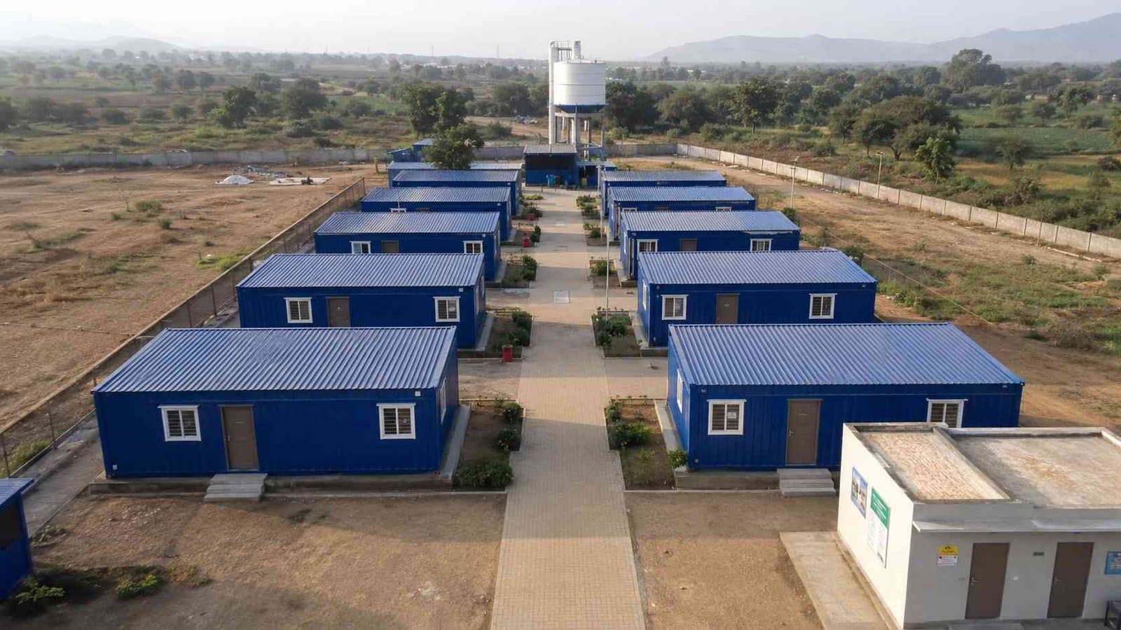 Colony of eight to ten SAMAN Royal Cobalt prefab container homes arranged in two rows for staff accommodation on an Indian project site.