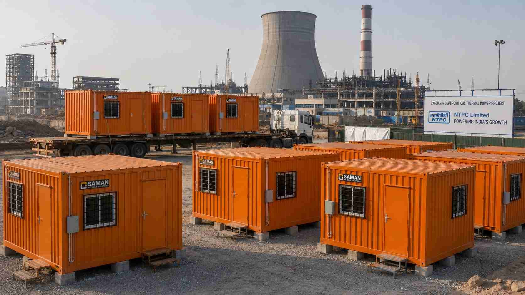 Safety Orange SAMAN prefab labor hutments arriving on a 32 ft trailer at a thermal power plant construction site.