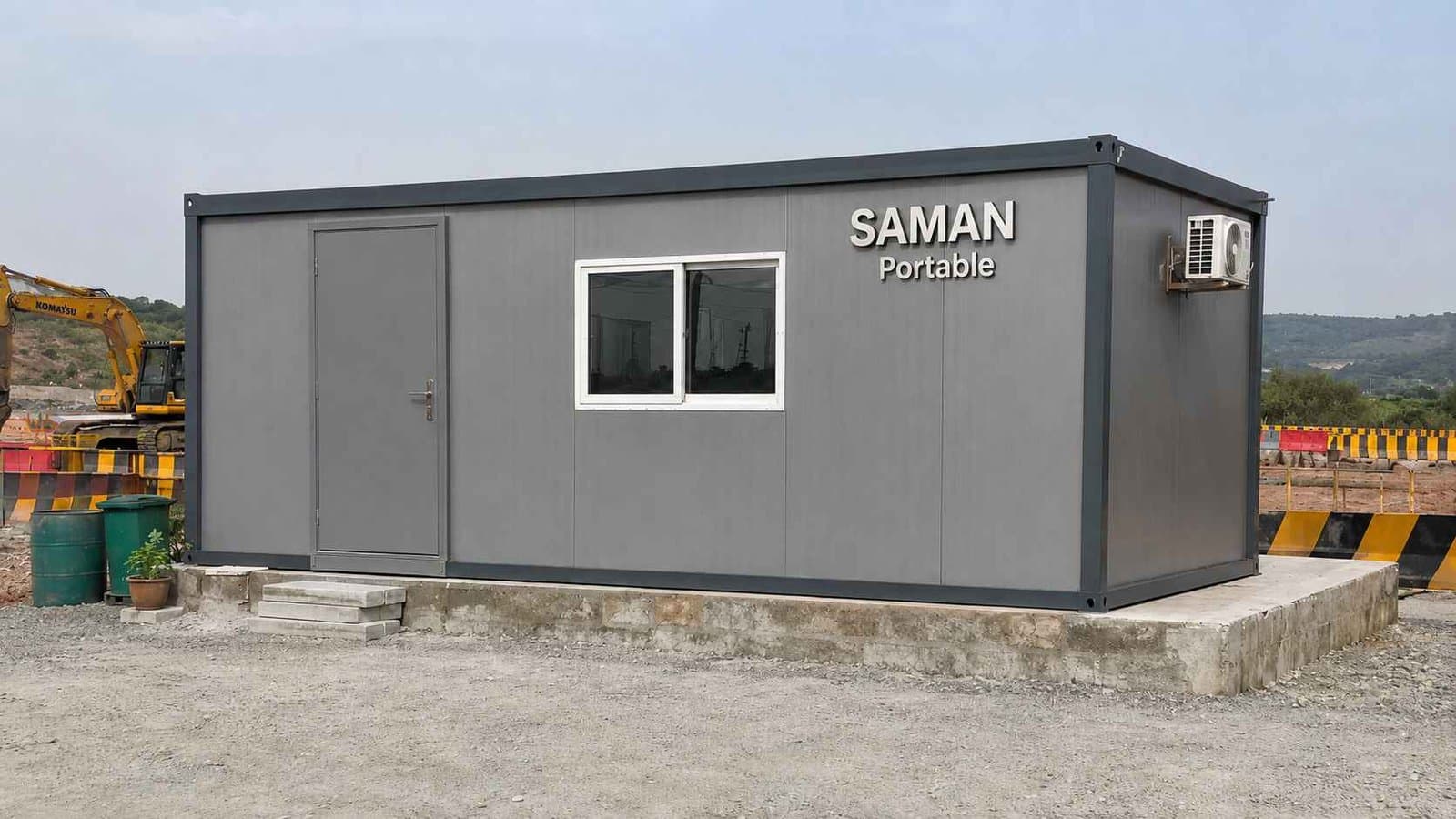 Steel grey prefab office building at an Indian highway construction site with equipment behind