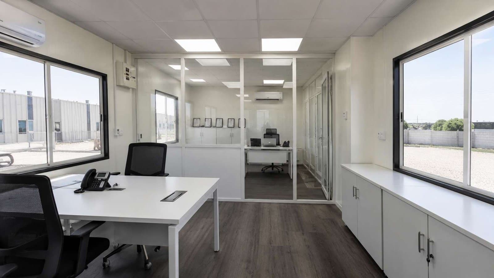 Interior of prefab office building with white partitions forming reception and a manager cabin