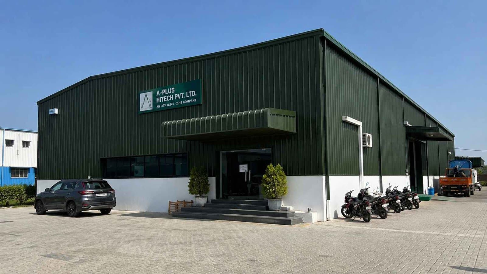 Forest-green prefabricated commercial building in use on an Indian industrial estate.