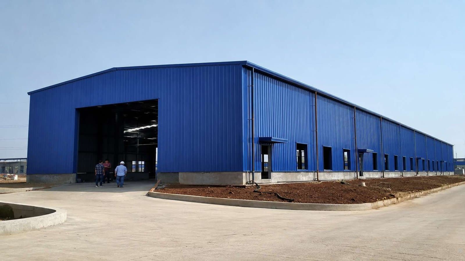 Royal-cobalt prefabricated steel building nearing completion on an Indian industrial plot.