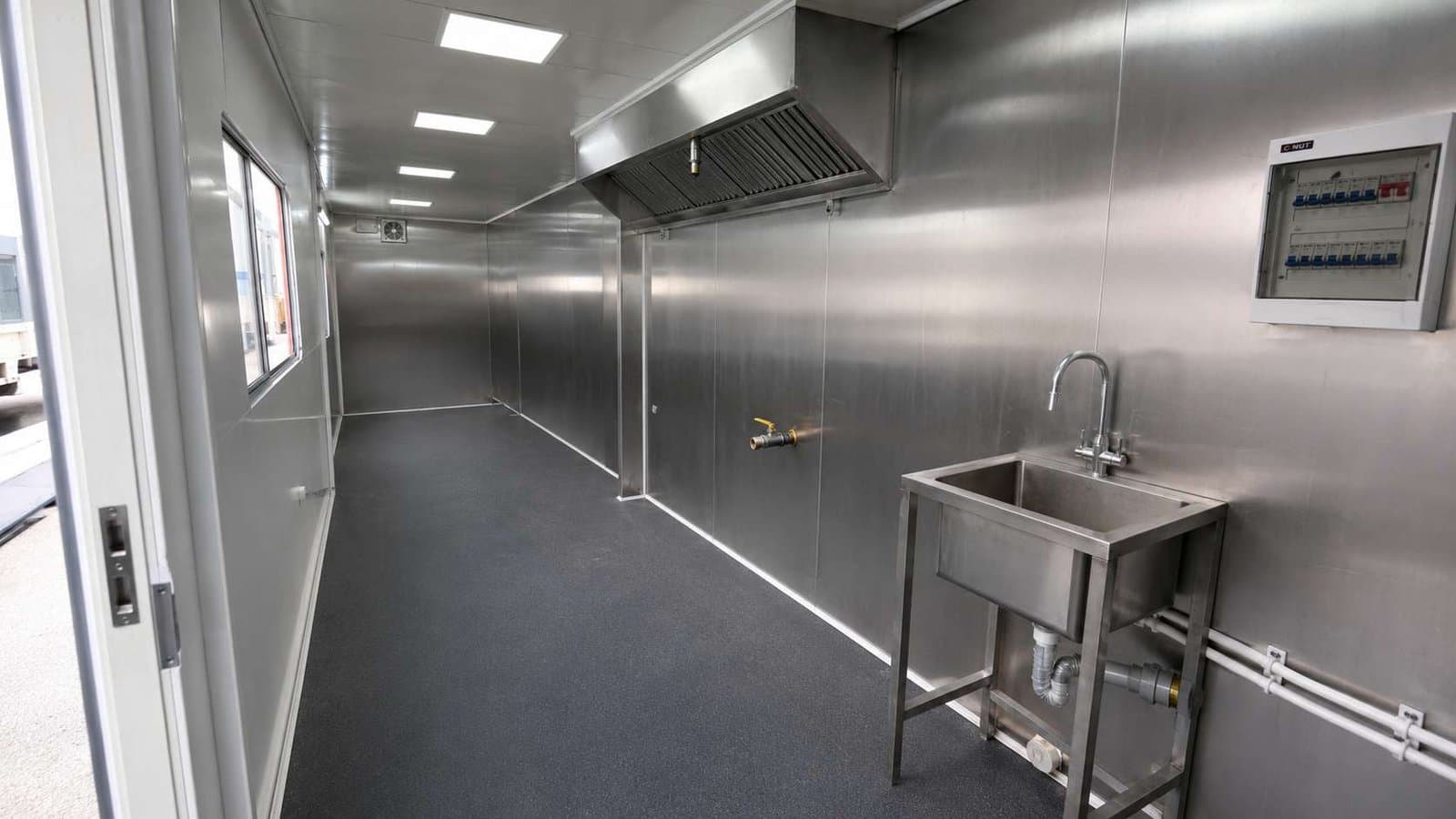 Interior of a SAMAN restaurant food container showing the food-grade stainless steel cooking wall, commercial exhaust hood, sink, and MCB panel