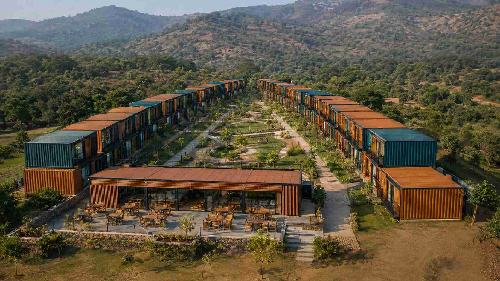Aerial view of a 50-key shipping container hotel resort with stacked container rows around a central courtyard and dining block
