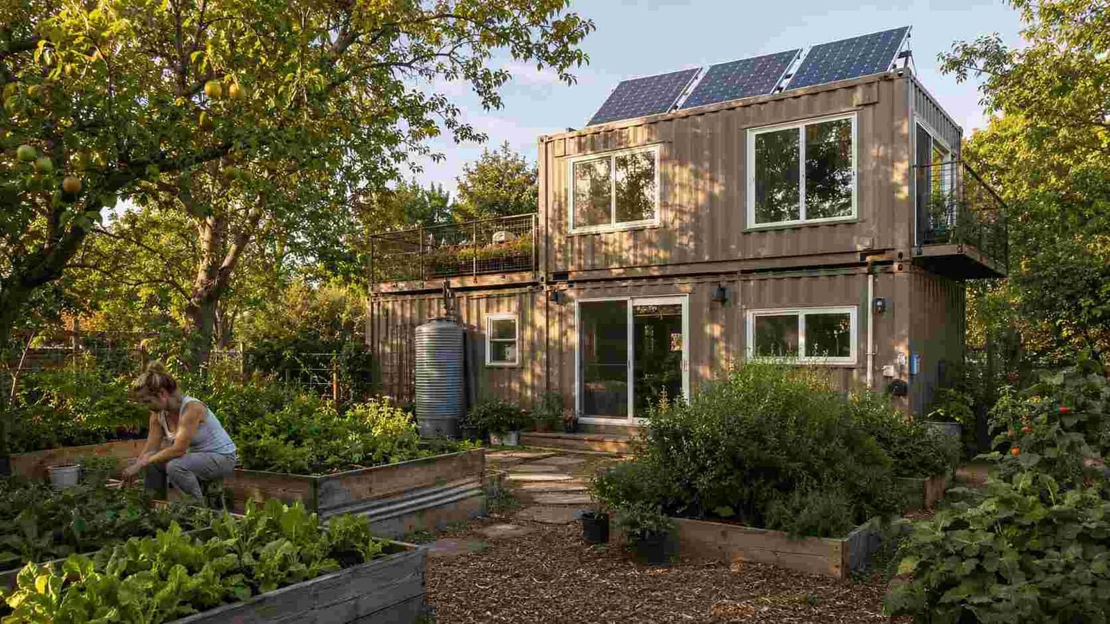 shipping container tiny house in eco garden setting with solar panels warm taupe exterior and vegetable planters