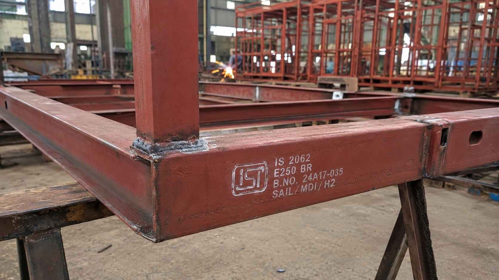 IS 2062 Grade A mild steel porta cabin base frame in Brick Red primer during fabrication at an Indian factory.