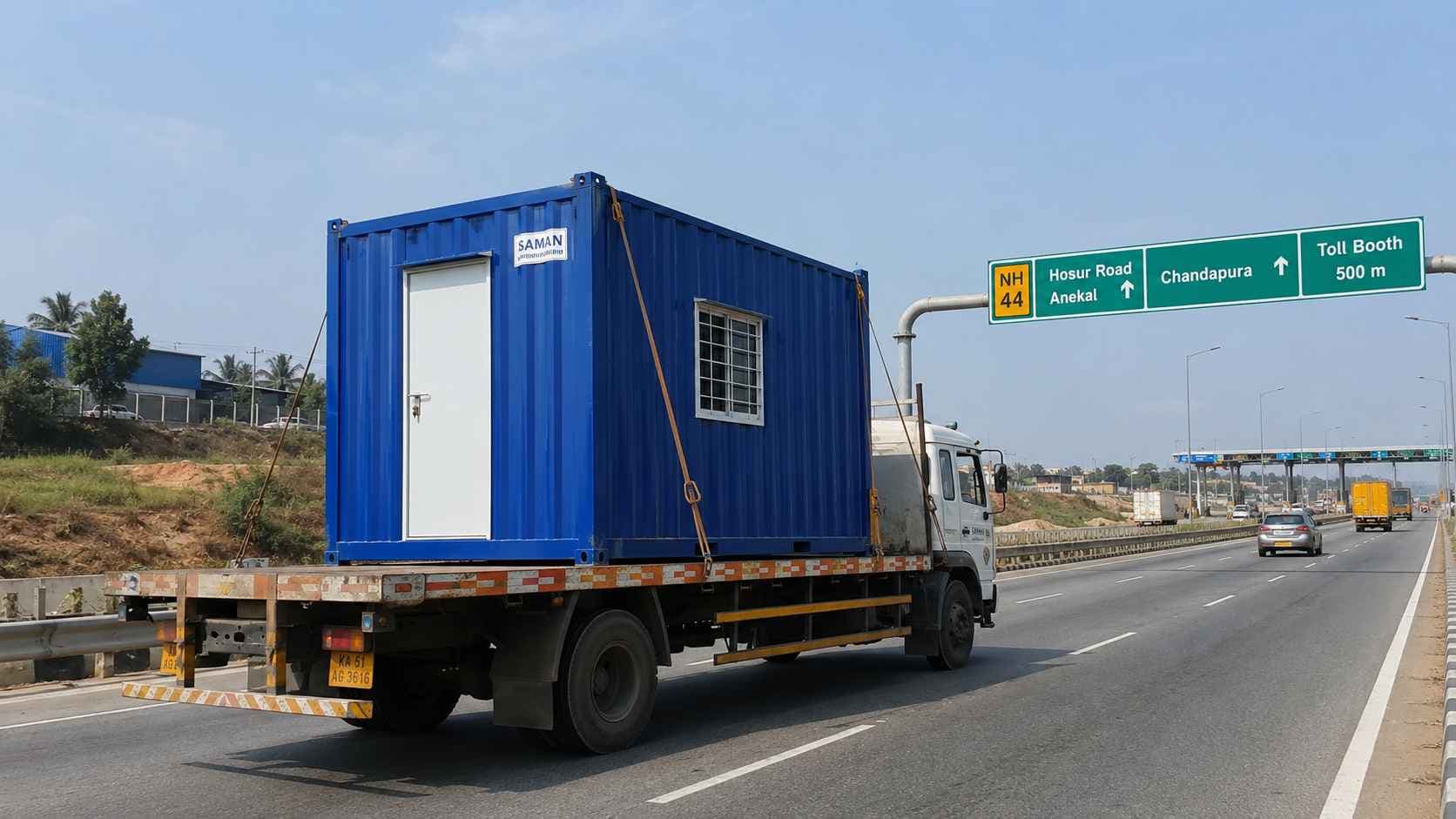 Royal Cobalt SAMAN porta cabin on a flatbed truck on NICE Road heading from Gopasandra factory to a KIADB Anekal plot.