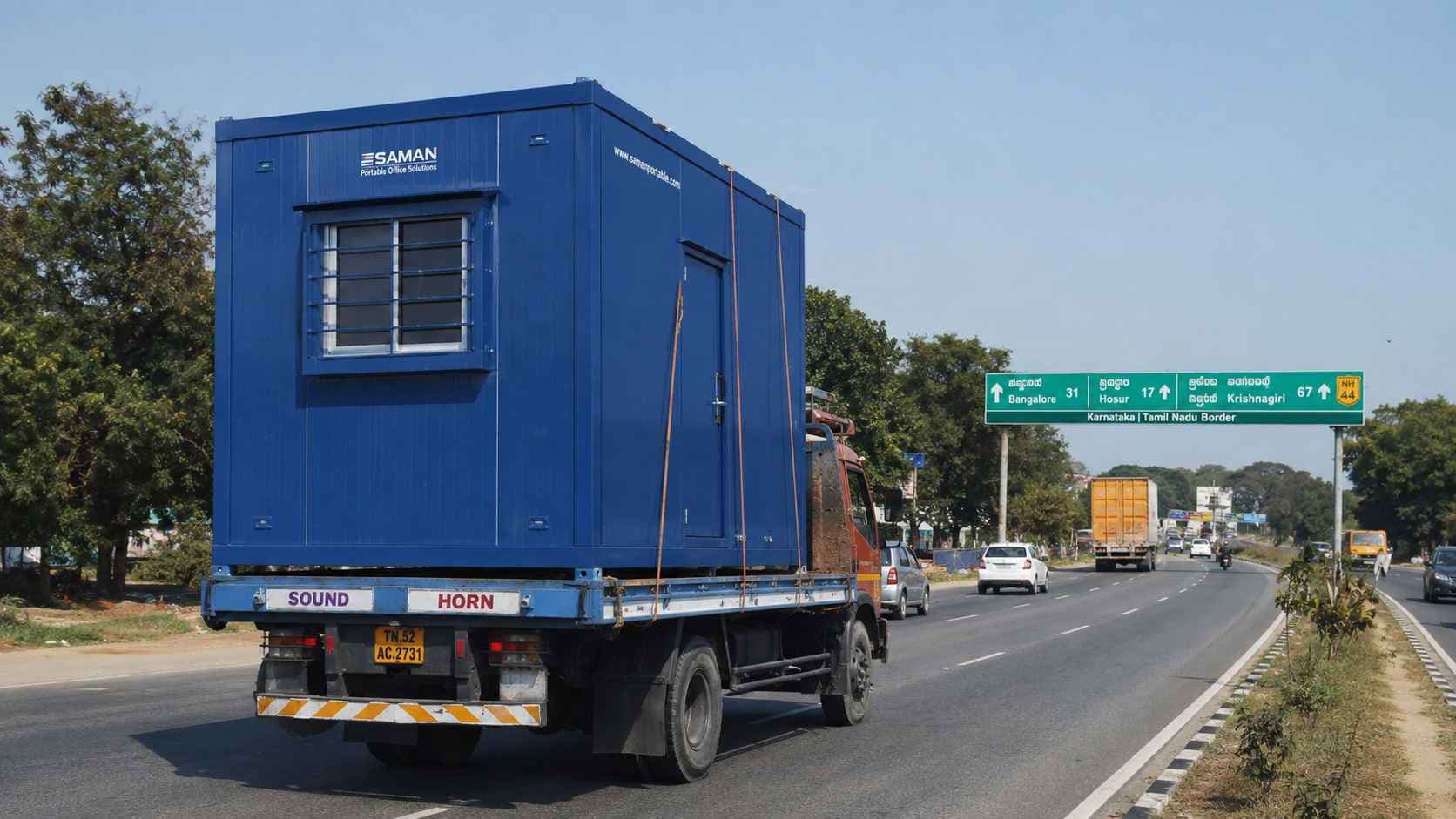 SAMAN NHAI Blue porta cabin loaded on a flatbed truck on NH 44 Bangalore-Hosur highway.