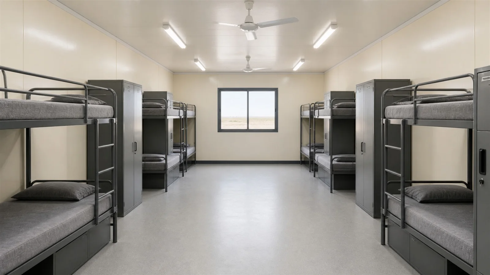 Wide-body oil field camp module interior with bunk frames along both walls and a central aisle